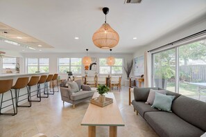 A modern kitchen with a dining area, large windows, and a cozy seating area with a sofa and chairs. - Private Palm Beach Pool Home Putting Green near BEACH Restaurants (North Palm Beach)
