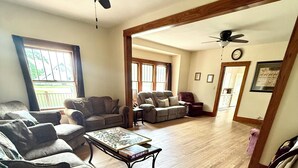 A living room with a wooden floor, a sofa, a coffee table, and a ceiling fan.