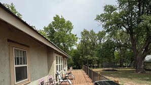 A deck with a grill, lounge chairs, and a house with a window.