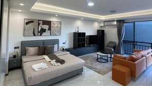 A modern bedroom with a large bed, a seating area with a sofa and armchair, a TV, and a balcony with a view. - Trendy Oasis Park Studio in Kimihurura - Kigali (Kigali)