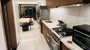 A modern kitchen with a gas stove, microwave, and stainless steel appliances. - Trendy Oasis Park Studio in Kimihurura - Kigali (Kigali)