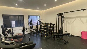 A modern gym with various exercise equipment, including a treadmill, weight bench, and free weights. - Trendy Oasis Park Studio in Kimihurura - Kigali (Kigali)