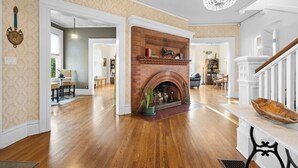 Un salon spacieux doté de parquet, d’une cheminée et d’un lustre.