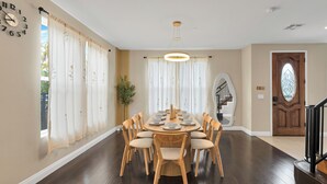 Una sala da pranzo con un tavolo rotondo apparecchiato per otto persone, circondato da sedie di legno con sedili imbottiti.