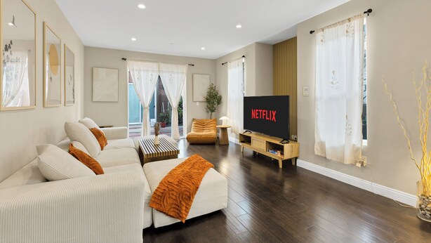 Un soggiorno moderno con un divano, una televisione e un pavimento in legno.