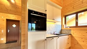 A compact kitchen with wooden walls, a built-in oven, and a window above the sink.