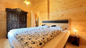 A wooden-paneled bedroom with a bed, a nightstand, and a hanging light fixture.