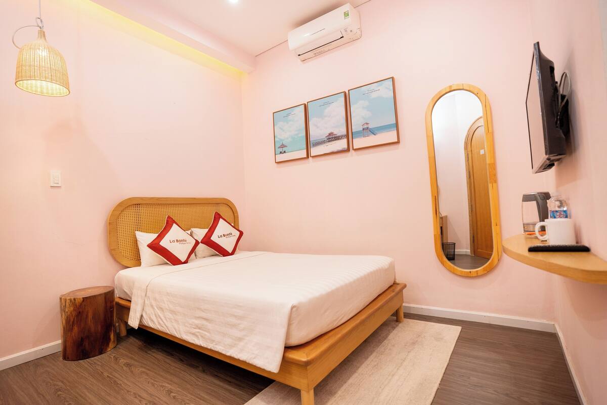 A bedroom with a wooden bed, a round mirror, a TV, and framed pictures on the wall.