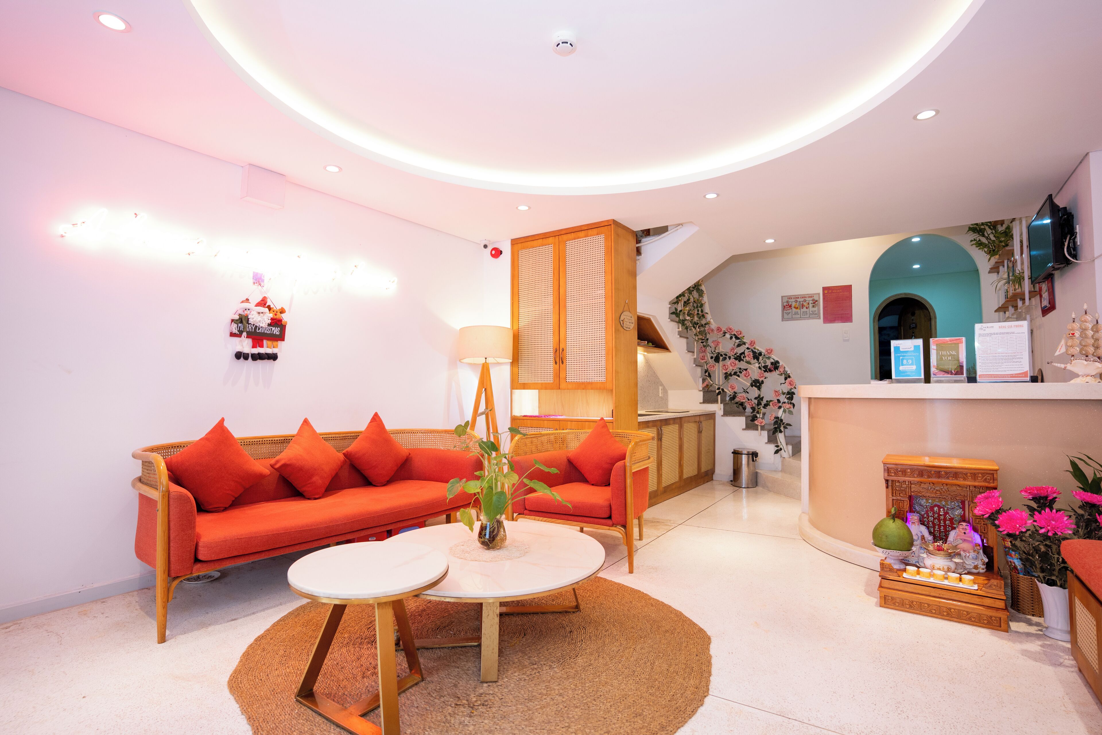 Un moderno vestíbulo de hotel con un mostrador de recepción, un conjunto de sofás, una pequeña mesa y un altar decorativo.