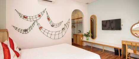 A bedroom with a bed, a TV, a mirror, a bench, and a wall decoration.