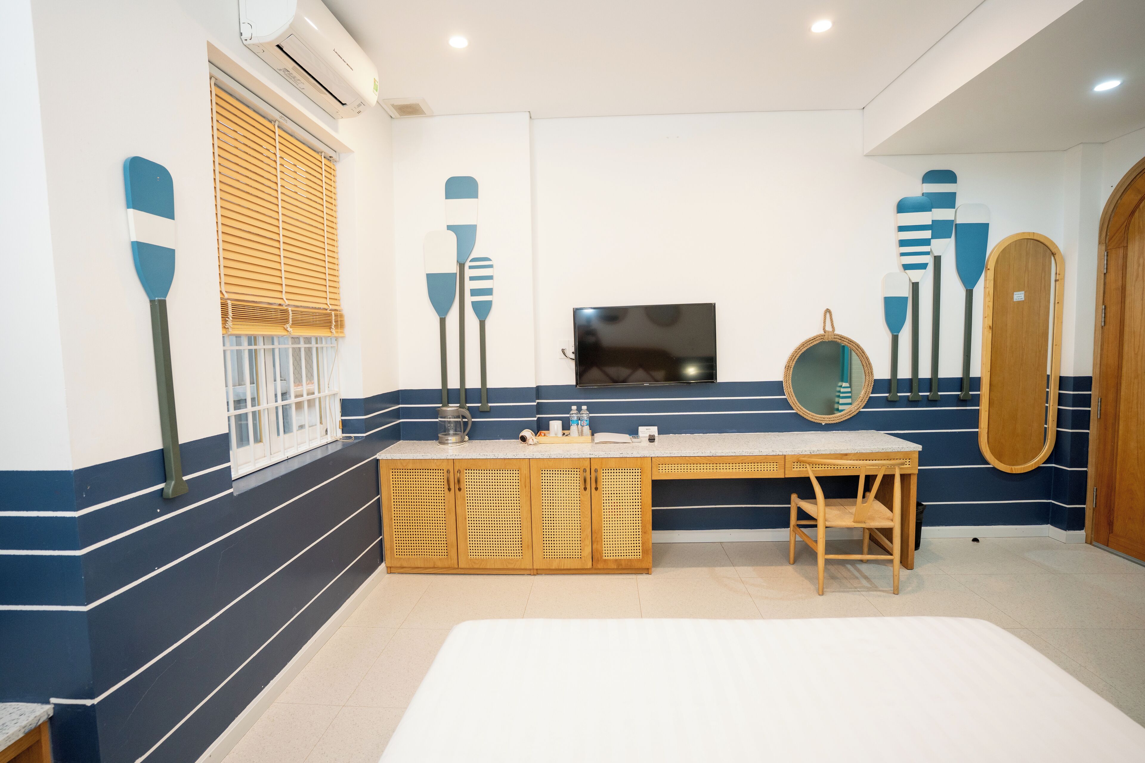 A bathroom with a wooden vanity, a mirror, and a window with blinds.