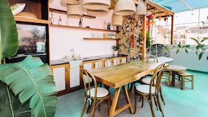 A dining area with a wooden table and chairs, a bar area with shelves and bottles, and a large green plant. - La Bonté Boutique Home Vung Tau (Ho Chi Minh City)