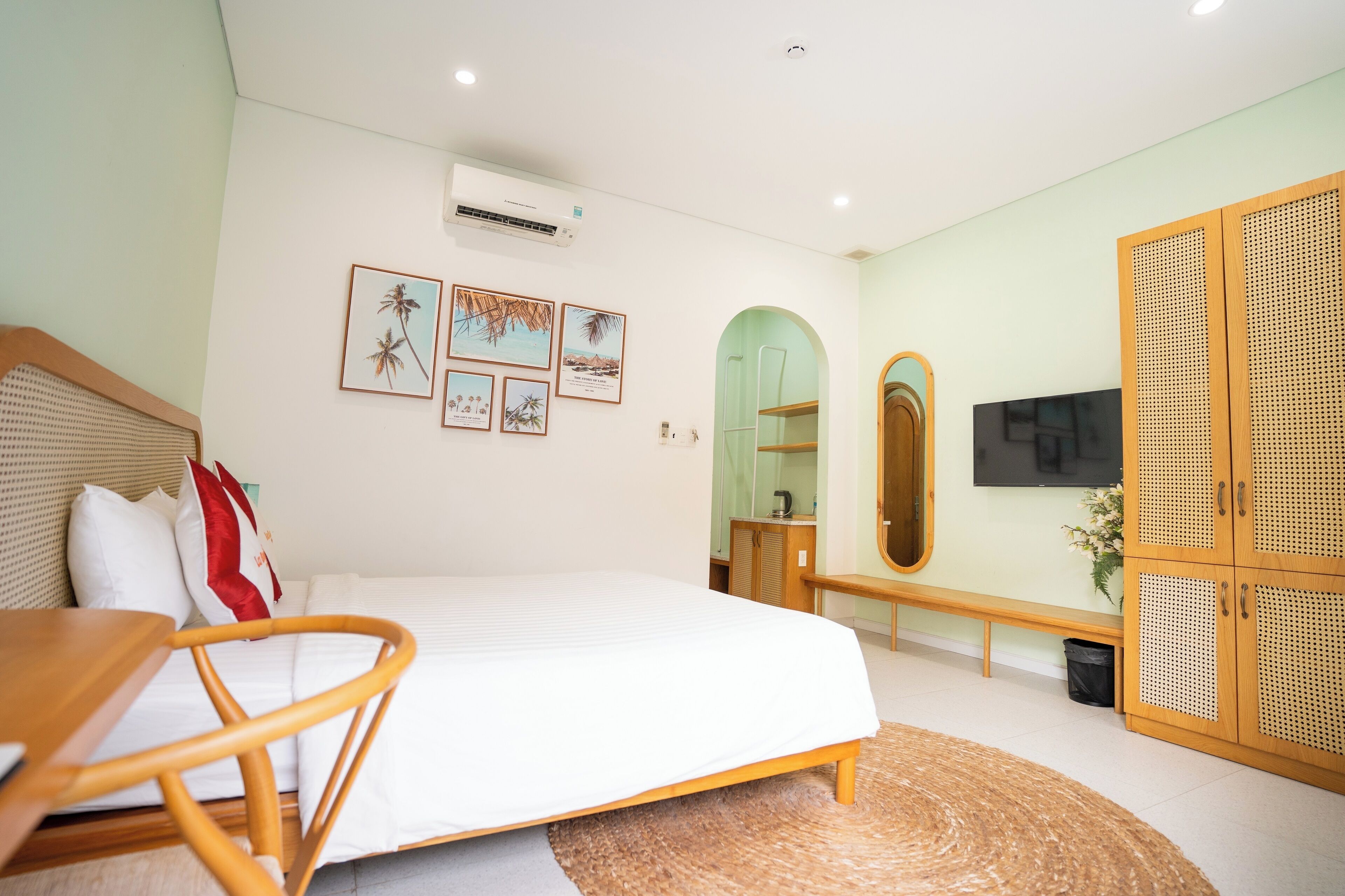 A modern bedroom with a bed, a wooden chair, a bench, a TV, and a wardrobe.