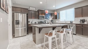 A modern kitchen with a large island, stainless steel appliances, and pendant lighting. - Clovis Gem – 4BR, 3.5 Bath (Clovis)