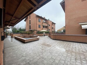 A courtyard with a brick building, a covered seating area, and a small water feature. - 10 min. from Maranello & Modena Golf Club—Cozy La Petite Maison (Emilia-Romagna)