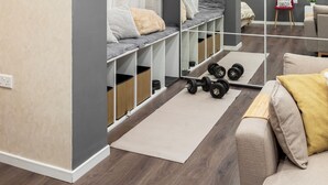 Una sala de estar moderna con una paleta de colores gris y blanco, un banco empotrado con espacio de almacenamiento, un televisor de pantalla plana y un espejo que refleja la habitación.