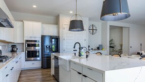 A modern kitchen with white cabinetry, stainless steel appliances, a marble island, and pendant lighting. - New Modern Luxury 8-bed mins to AAG, Fwy, Clubhouse. Ideal Sports or Ext Stay  (Mesa)