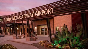 The Phoenix-Mesa Gateway Airport entrance with a baggage claim sign, outdoor lighting, and cacti landscaping. - New Modern Luxury 8-bed mins to AAG, Fwy, Clubhouse. Ideal Sports or Ext Stay  (Mesa)