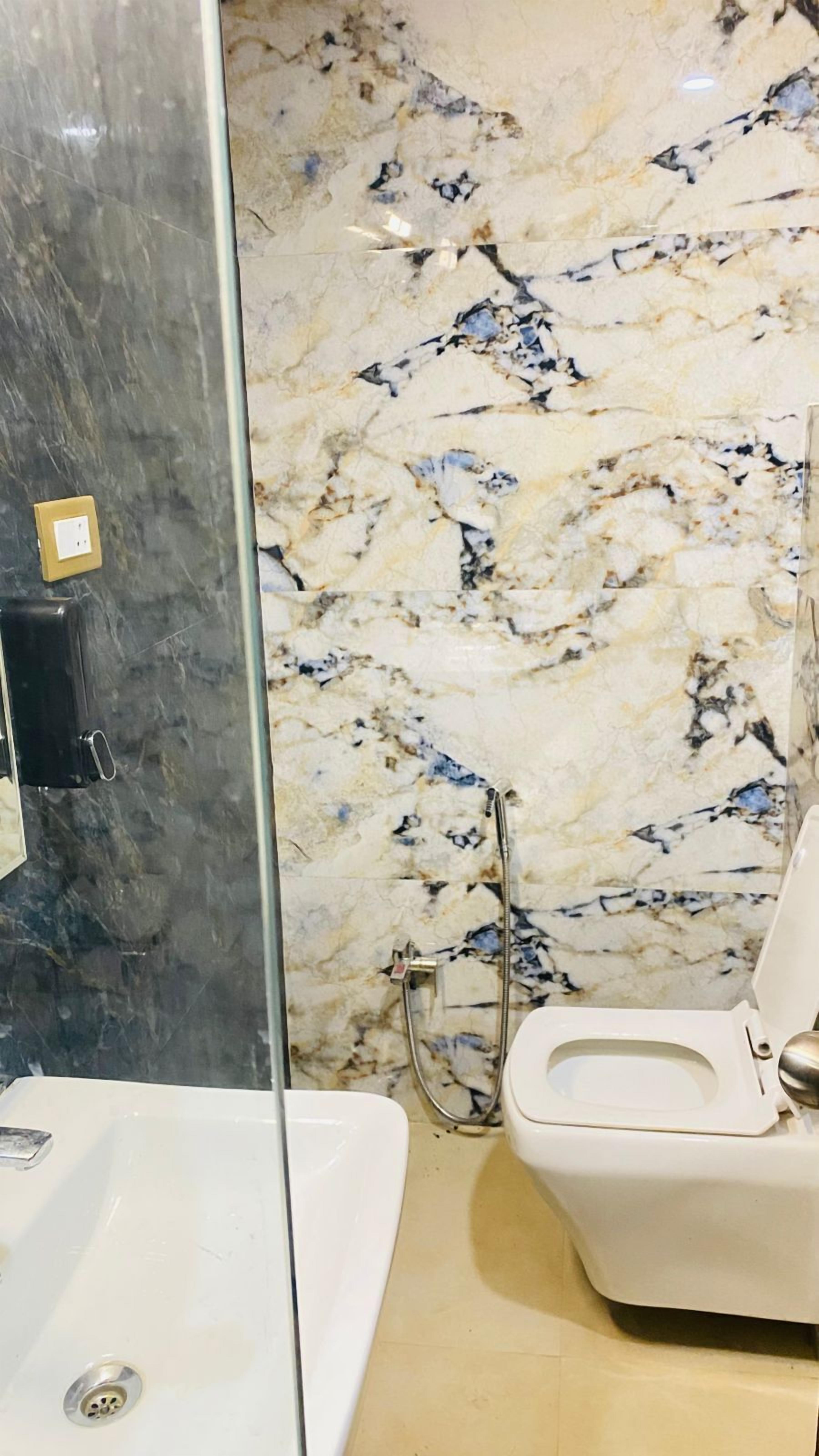 A bathroom with a marble backsplash, a white sink, and a toilet.