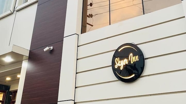 Un edificio moderno con fachada de vidrio reflectante, un cartel que dice "Skyline Inn" y varios ventanales.