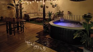 An outdoor patio with a hot tub, wooden furniture, and potted plants. - Sliema Pearl Luxury Apartment (Sliema)