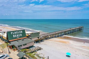 Vue sur la plage de Flagler Beach, avec une jetée qui s’avance dans l’océan, une maison de plage et un poste de surveillance des sauveteurs.