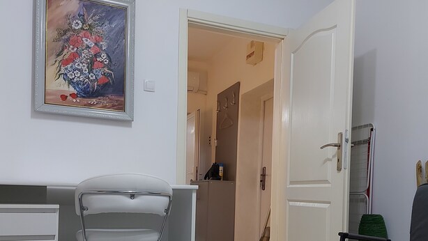Una sala de estar moderna con un escritorio blanco, un sofá gris y una mesa de comedor con un cuenco decorativo.