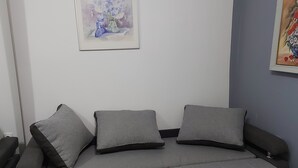 Un sofá gris con dos cojines, una mesita y dos cuadros enmarcados en la pared.