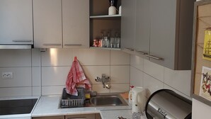 Una cocina moderna con armarios blancos, un lavamanos de acero inoxidable y una parrilla integrada.