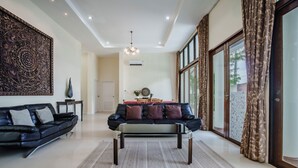 Ein geräumiges Wohnzimmer mit einer schwarzen Couch, einem Couchtisch und einem großen Wandbild.