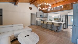 Una cocina moderna con una isla central, taburetes de bar y un comedor con mesa redonda.