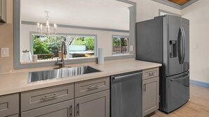 Una cocina moderna con un refrigerador de acero inoxidable, un lavamanos doble y una araña.