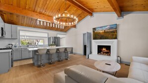 Una cocina moderna con una isla central, taburetes de bar y una chimenea.