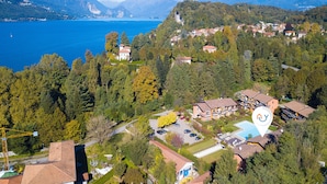 Vista aérea de una zona residencial con una gran masa de agua, montañas al fondo y una combinación de casas y vegetación.