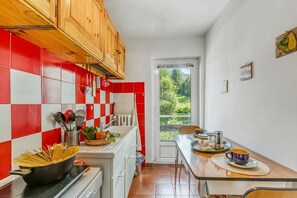 Una cucina con piastrelle rosse e bianche, mobili impiallacciati in legno, un piano cottura e un'area pranzo con tavolo e sedie.