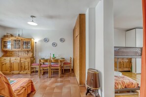 A compact room with a bunk bed, wooden furniture, a dining table with chairs, and a cabinet. - Gran Roc 23 (Sestriere)
