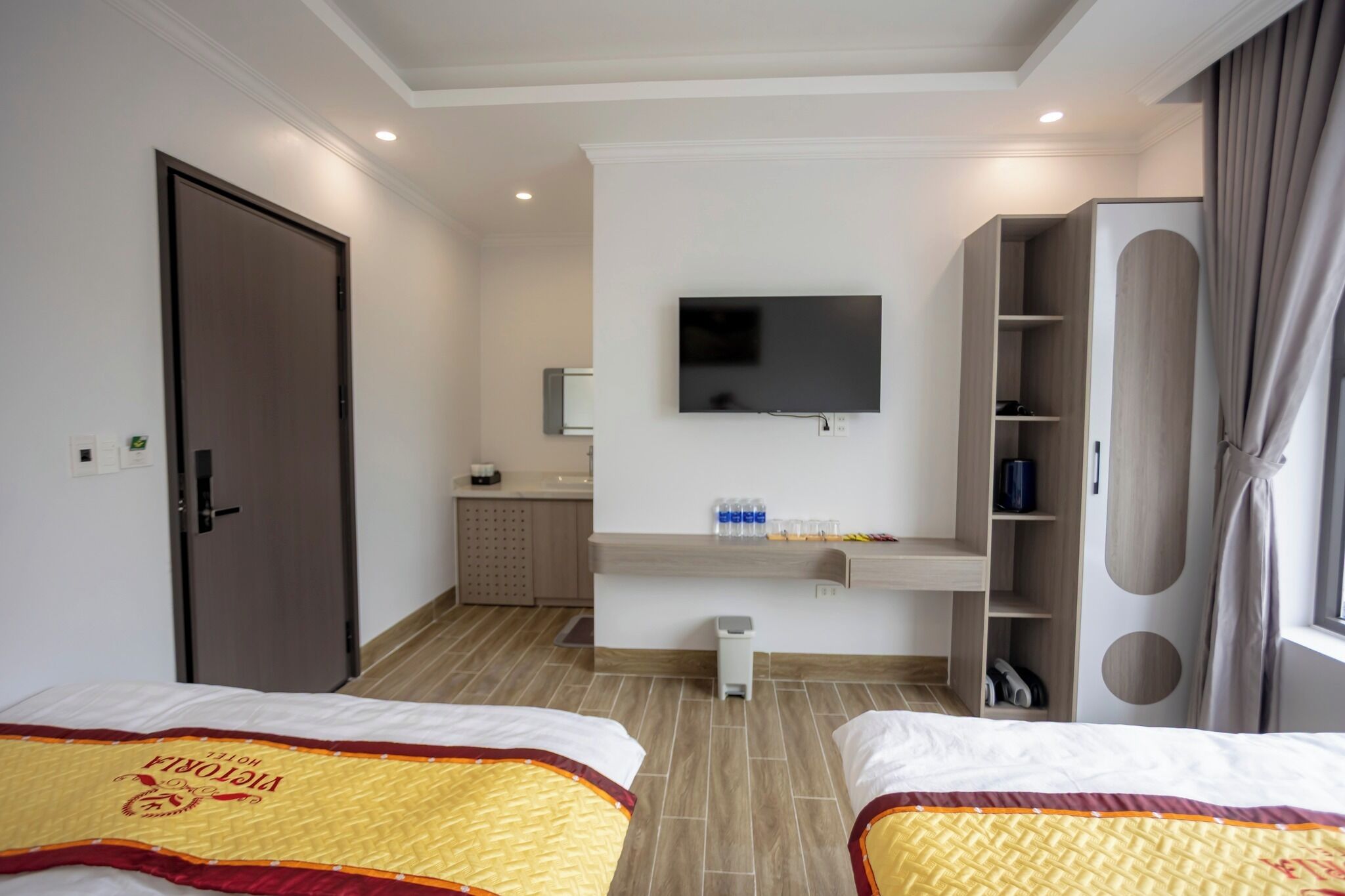 Une chambre d’hôtel avec deux lits, une télévision, une petite kitchenette et une armoire.