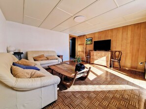 Una sala de estar con sofá, mesa de centro y televisor.