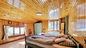 Een houten slaapkamer met twee bedden, een kledingkast en een raam met gordijnen.