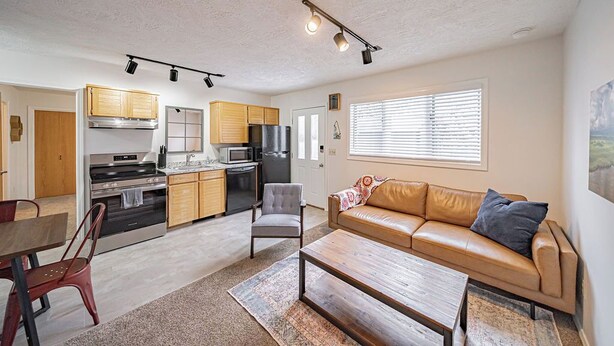 Una cocina moderna con electrodomésticos integrados, un comedor con mesa y sillas, y una sala de estar con sofá y mesa de centro.