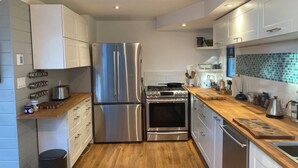 Una cucina moderna con elettrodomestici in acciaio inossidabile, piani di lavoro in legno e mobili bianchi.