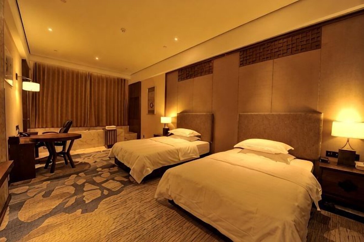 A hotel room with two beds, a desk, and a chair.
