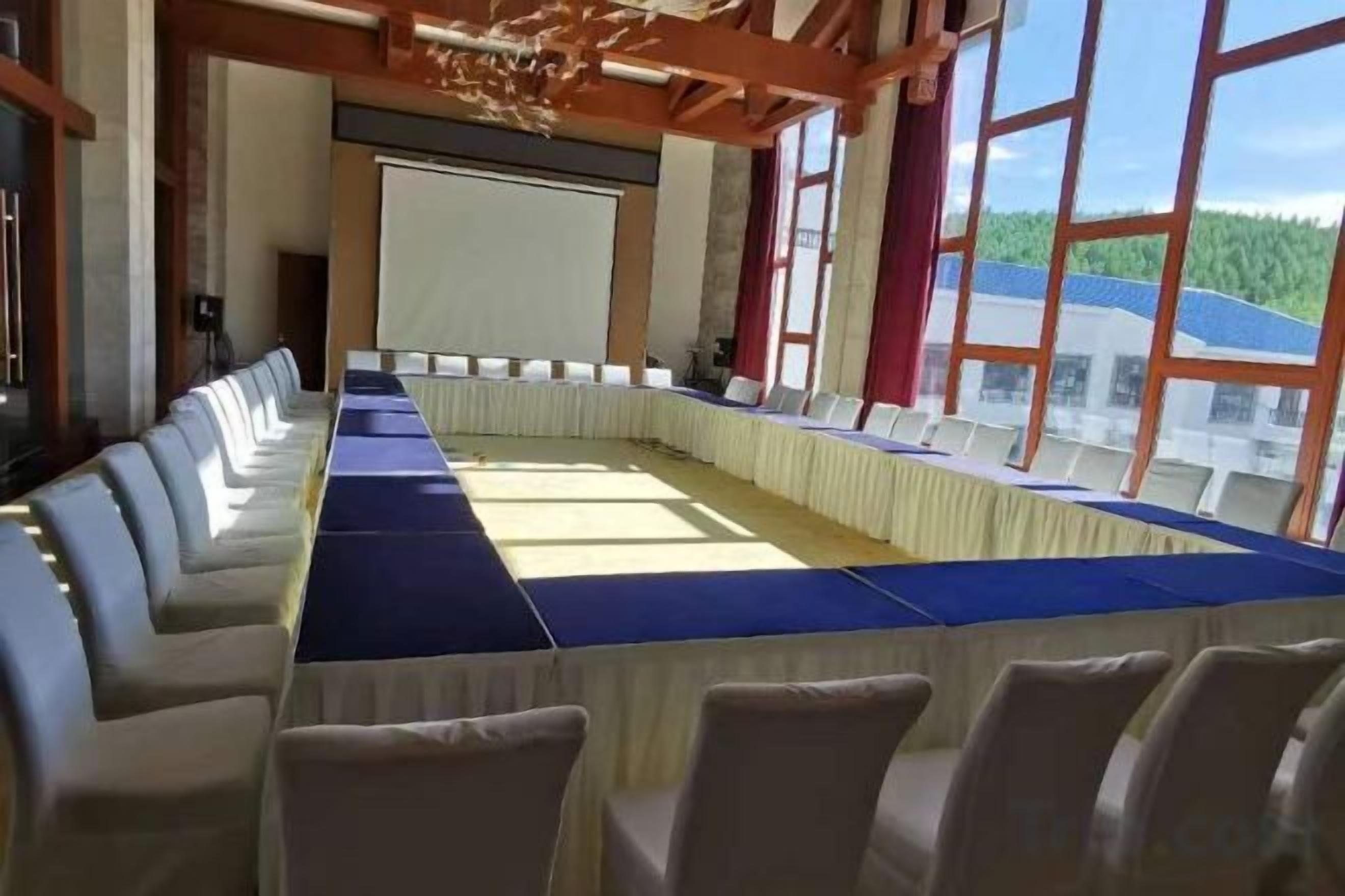 Een vergaderzaal met een lange tafel, stoelen en een projectiescherm.