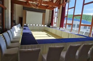 Un salón de conferencias con una larga mesa, sillas y una pantalla para proyector.