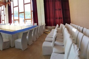 Un salón de conferencias con una larga mesa y filas de sillas.