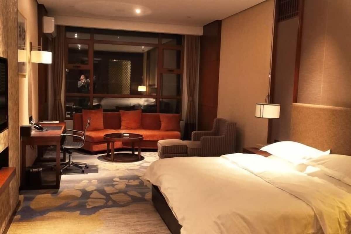 Een hotelkamer met een bed, een bank, een bureau, een stoel en een kleine tafel.