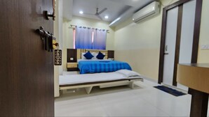 Ein Schlafzimmer mit Bett, Holztür, Klimaanlage und Deckenventilator.