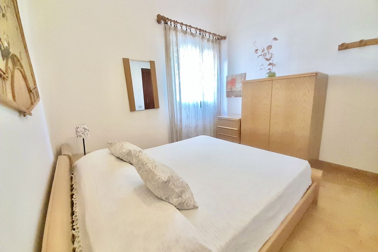 Une chambre à coucher avec un lit, une armoire, un miroir et une fenêtre avec des rideaux.