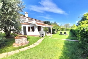 A white house with a tiled roof, a stone fireplace, and a well-maintained lawn. - <i>Reclaim your own space on Sardinia's south-eastern coast, in a secluded, sheltered home a stone's throw from the sea and the heart of Costa Rei.</i>Just steps from the <b>centre of Costa Rei</b> and only <b>300 metres from the white sandy beach</b>, < (Muravera)