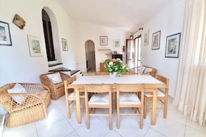 A dining area with a wooden table and chairs, surrounded by wicker chairs with cushions. - <i>Reclaim your own space on Sardinia's south-eastern coast, in a secluded, sheltered home a stone's throw from the sea and the heart of Costa Rei.</i>Just steps from the <b>centre of Costa Rei</b> and only <b>300 metres from the white sandy beach</b>, < (Muravera)